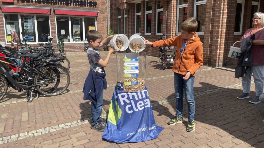 Kinderen stoppen de gevonden sigarettenpeuken tijdens de Rhine Clean Up op 8 mei in de bak